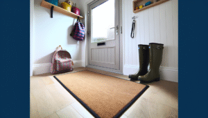 Stylish machine washable door mat in a clean, modern UK entryway with signs of a busy family life, like wellington boots and school bags.